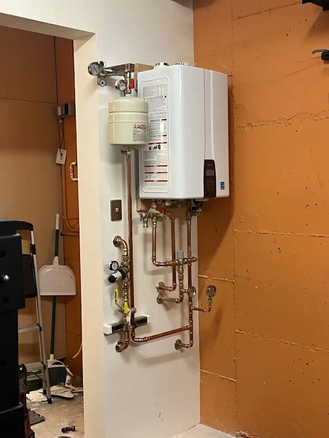 Plumbing technician inspecting water heater connections in Wayland